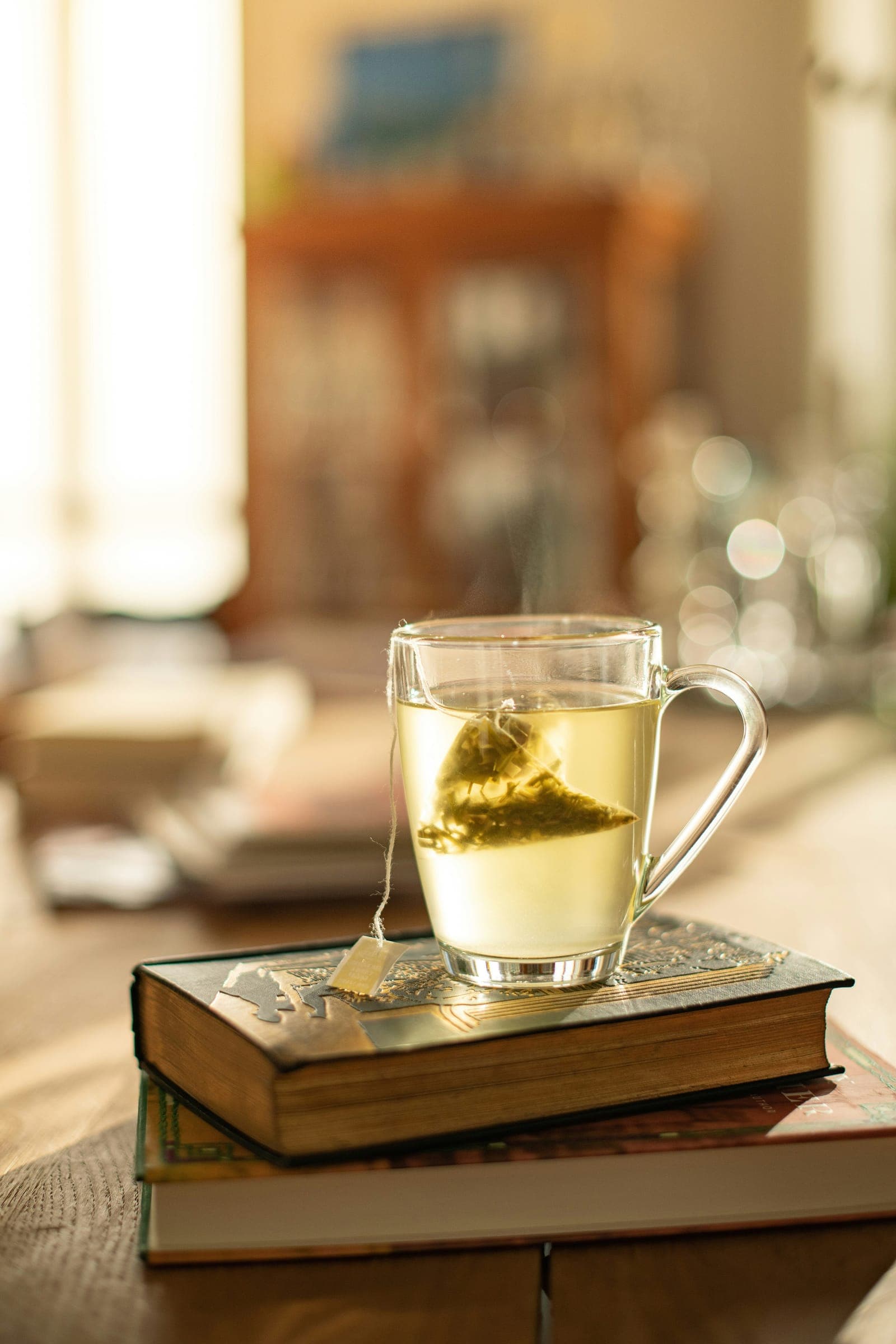 A glass mug of pale golden herbal tea in soft evening light
